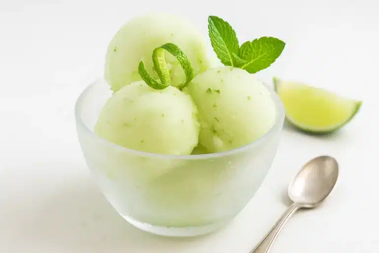 Easy Lime Sorbet Recipe | Refreshing Dairy-Free Dessert Lime sorbet in a frosted bowl with mint leaves and lime zest garnish on white background