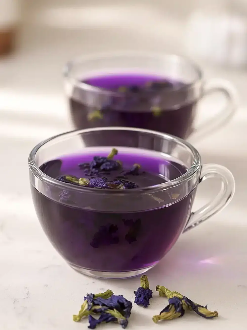 Brazilian Mounjaro recipe – a vibrant purple detox herbal tea served warm in a clear glass, featuring a natural and calming color-changing effect.