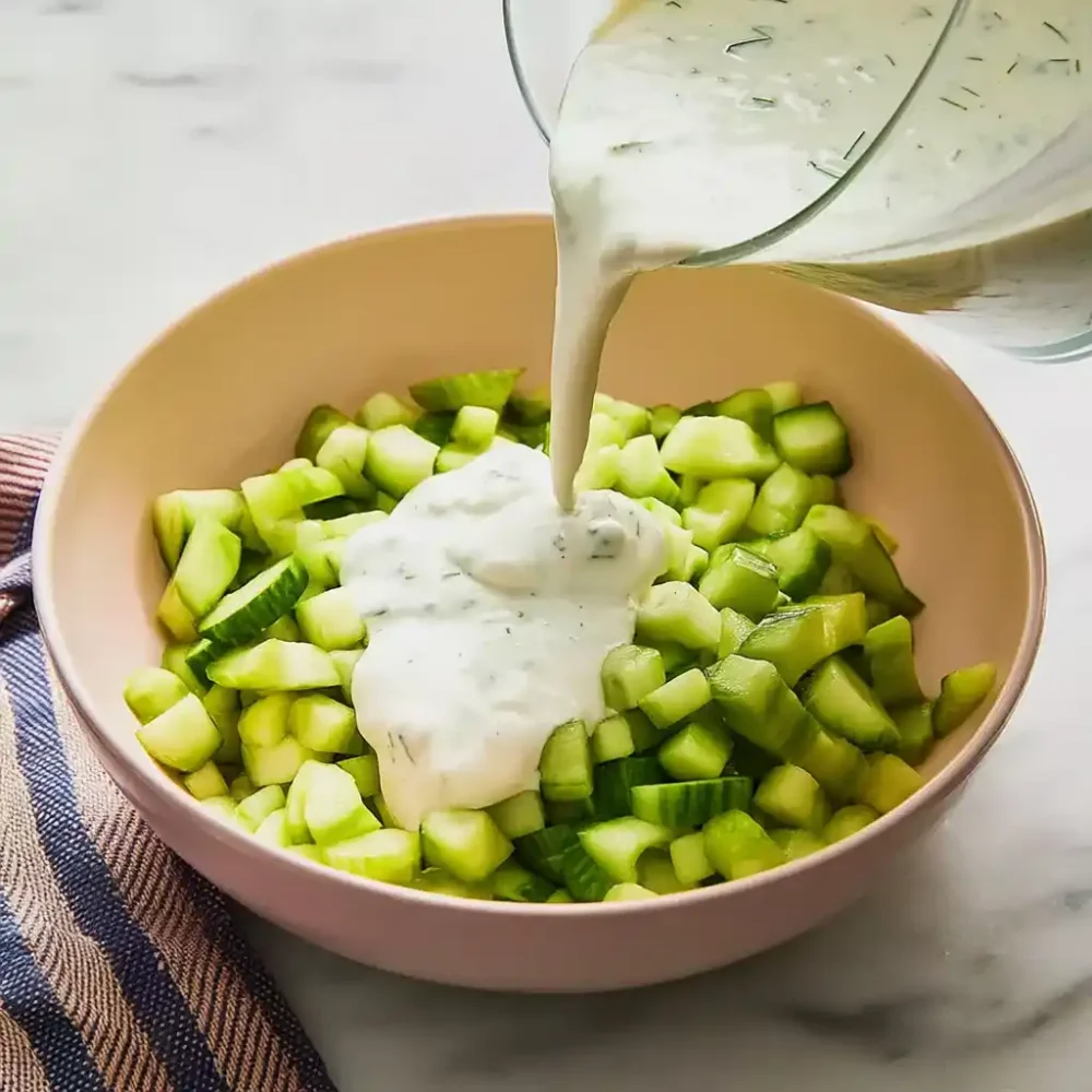 Cucumber Yogurt Salad Protein That’s Fresh, Light and Full of Flavor yogurt being poured over cucumbers for salad protein