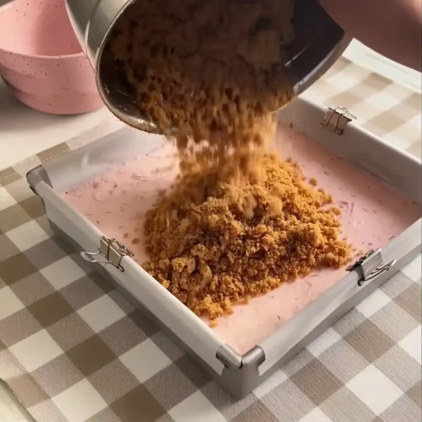 Strawberry ice cream sandwiches graham crust being added by hand