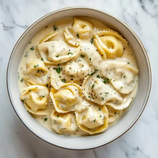 tortellini with alfredo sauce and fresh basil served in a speckled ceramic bowl