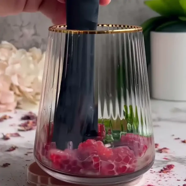 Hand muddling raspberry lime mojito mocktail in a tall clear glass