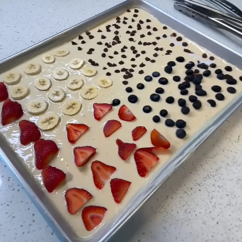 Sheet pan pancake batter with strawberries, blueberries, and bananas ready for baking