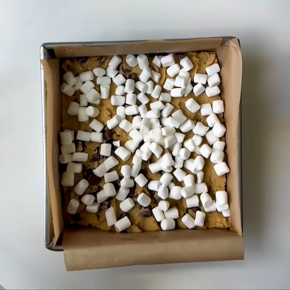 S’mores Cookie Bars: Gooey, Crunchy & Chocolatey in Every Bite S’mores Cookie Bars in a pan, topped with chocolate chips and marshmallows