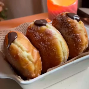 Chocolate Bomboloni – Italian Cream-Filled Delight Golden Chocolate Bomboloni rolled in sugar, soft and fluffy