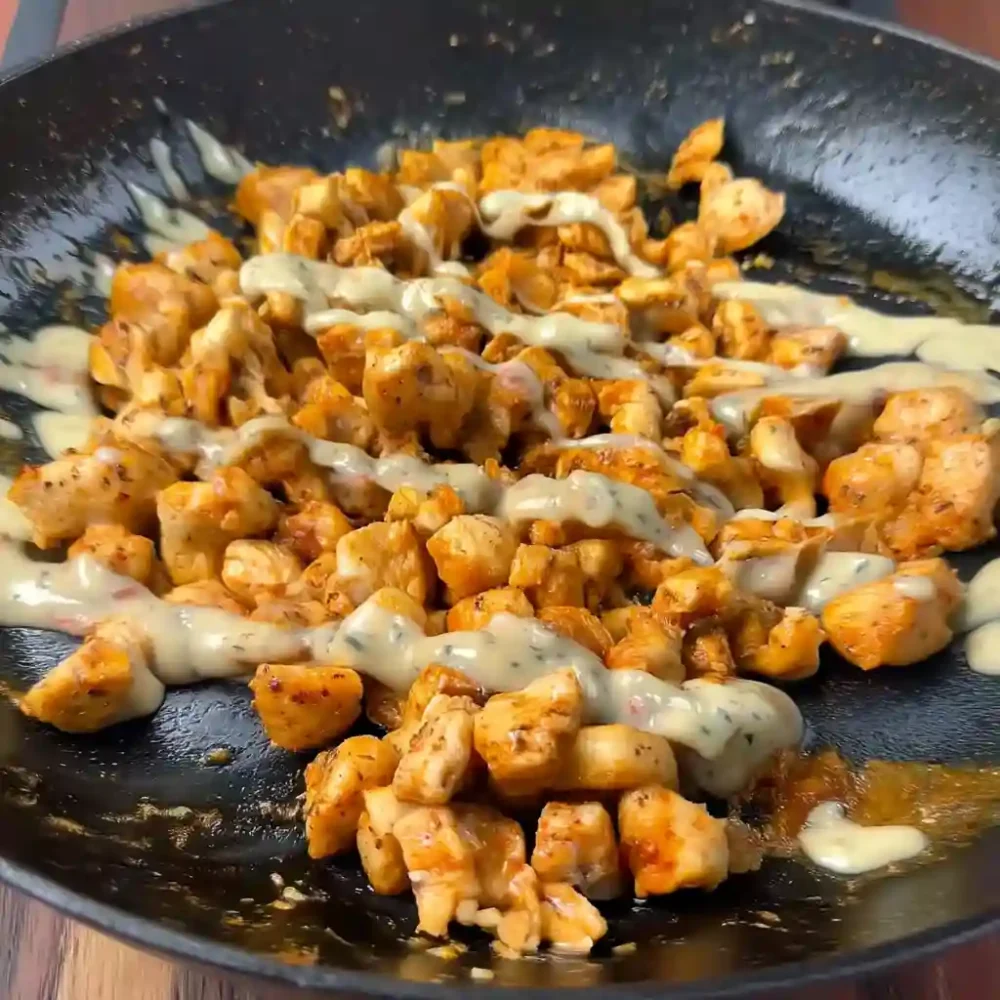 Juicy chicken pieces topped with creamy garlic Parmesan sauce in a skillet