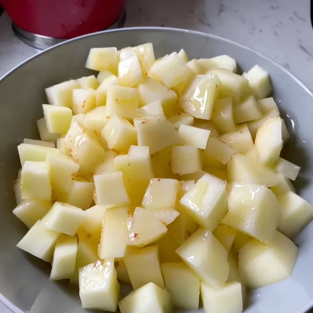 Cubed potatoes tossed in oil and seasoning for Garlic Parmesan Chicken and Potato Skillet