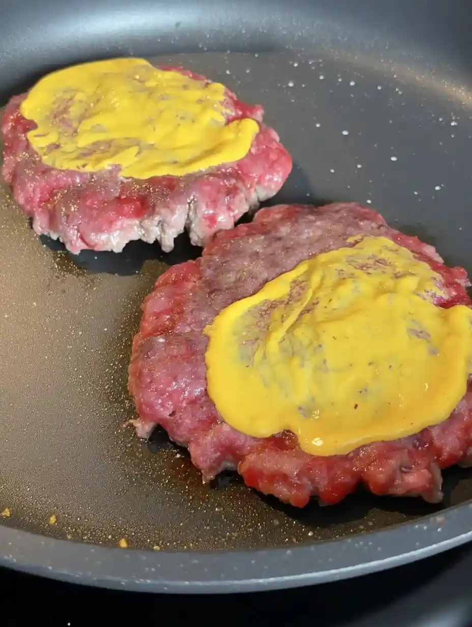 Copycat In-N-Out Burgers and Fries – The Ultimate Guide Two beef patties cooking in a skillet with mustard for Copycat In-N-Out Burgers and Fries