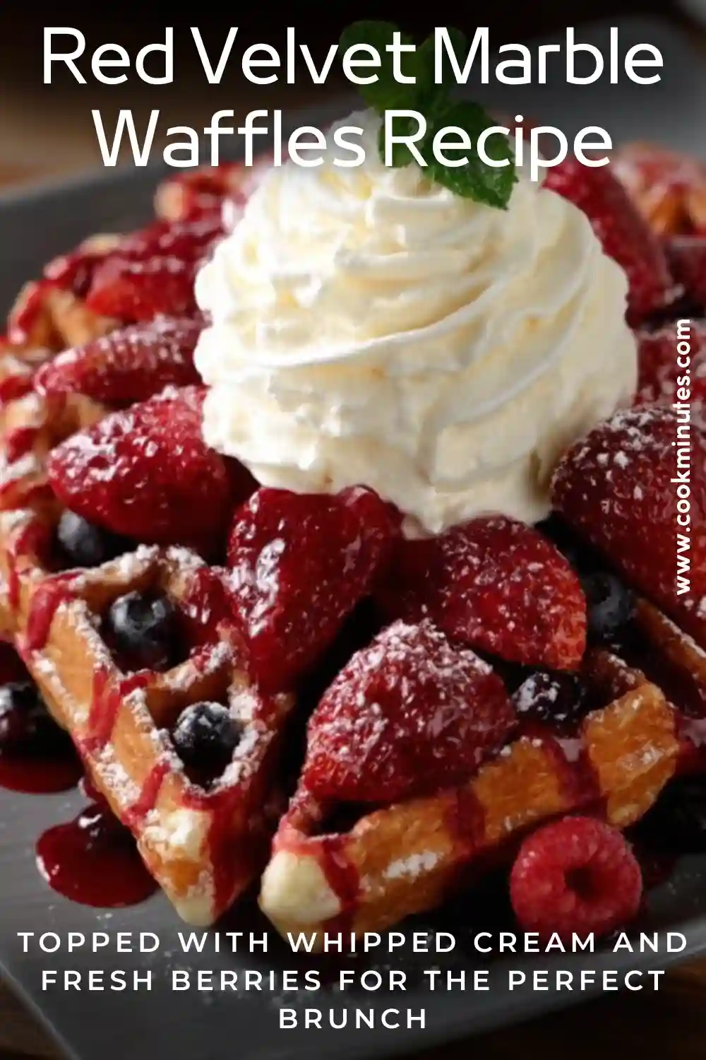 Red Velvet Marble Waffles topped with whipped cream, strawberries, raspberries, and blueberry sauce on a gray plate