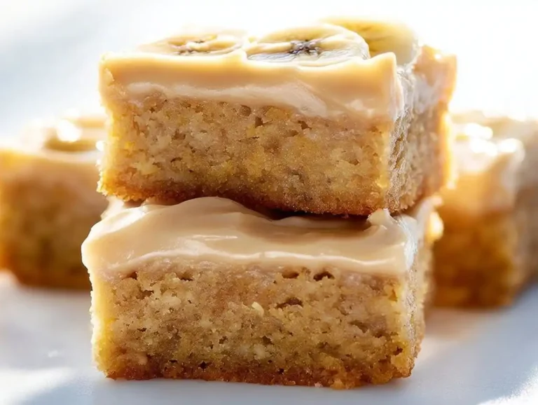 Banana Bars – Ooey Gooey Treats with Salted Caramel Frosting Delicious ooey gooey banana bars topped with frosting and banana slices.