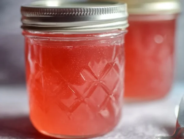 Homemade rhubarb jelly in a jar with fresh rhubarb stalks