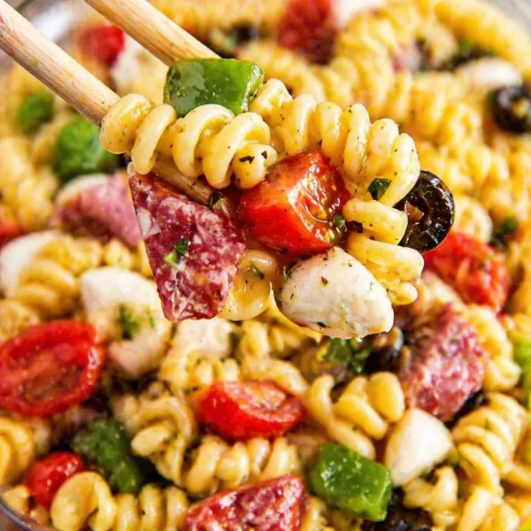 Cold pasta salad for BBQ with colorful vegetables and dressing.