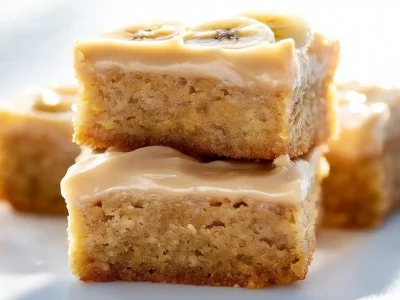 Delicious ooey gooey banana bars topped with frosting and banana slices.