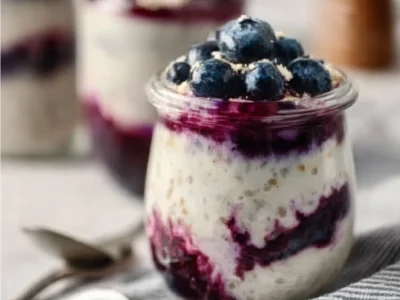 Blueberry cheesecake overnight oats topped with fresh berries and nuts.