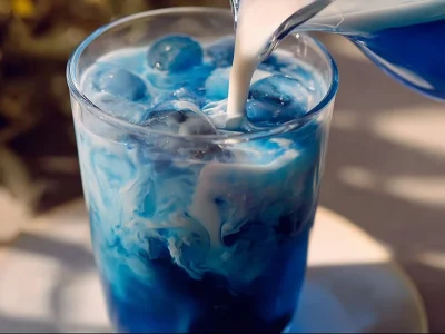 Glass of butterfly pea tea refresher with lemon and mint garnish