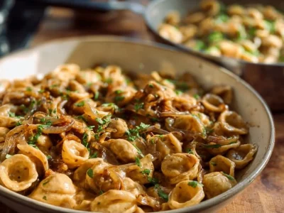 Bowl of caramelized onion pasta topped with herbs and cheese