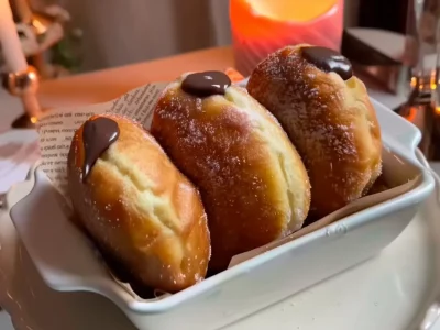 Chocolate Bomboloni – Italian Cream-Filled Delight Golden Chocolate Bomboloni rolled in sugar, soft and fluffy