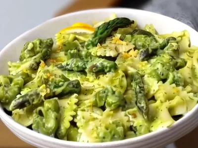 Plate of asparagus pasta topped with fresh herbs and parmesan cheese