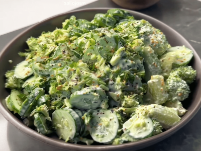 Bowl of creamy cucumber avocado broccoli salad with sliced cucumbers, chopped broccoli, and herb dressing.