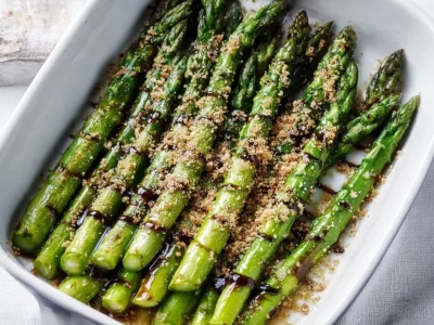Flavorful asparagus drizzled with balsamic glaze on a white plate.