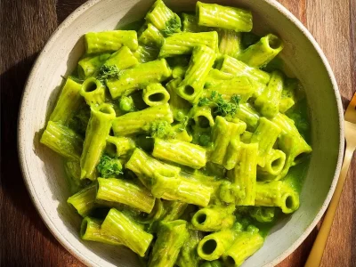 Vegan creamy spinach garlic pasta with cashews and parsley served in a bowl.
