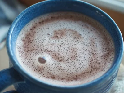 A cozy cup of warm maple vanilla almond milk topped with almonds and maple syrup.