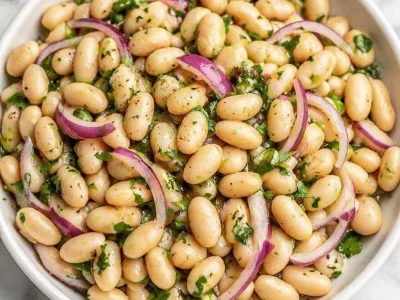 Fresh White Bean Salad with Lemon Vinaigrette, herbs, and red onion served in a bowl.